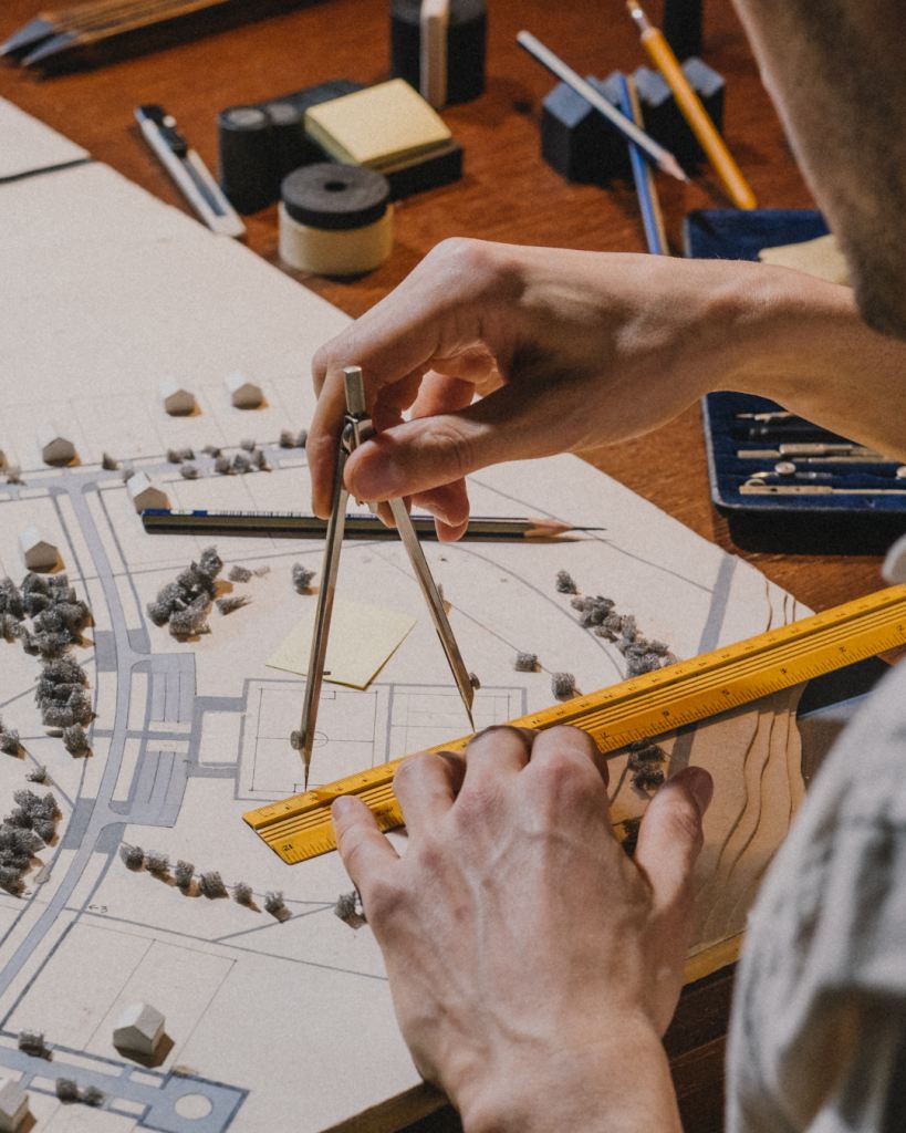 Des mains qui tracent au compas sur un plan d'habitation