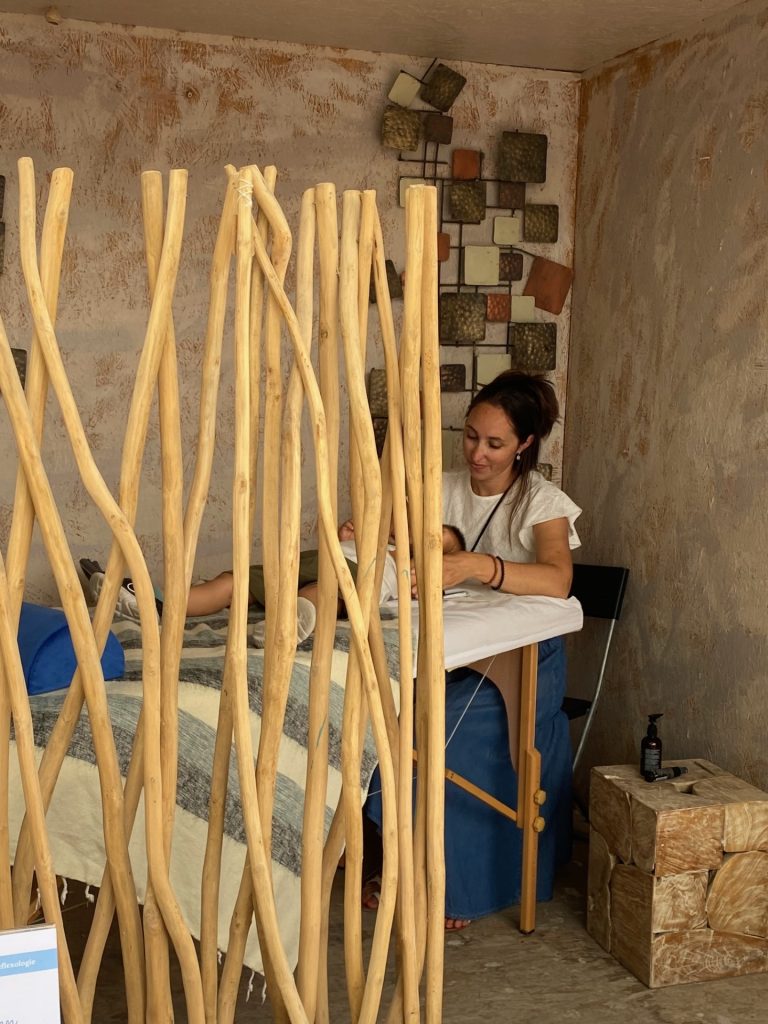 Lucie pendant une séance de réflexologie plantaire, derrière un paravent en bois flotté