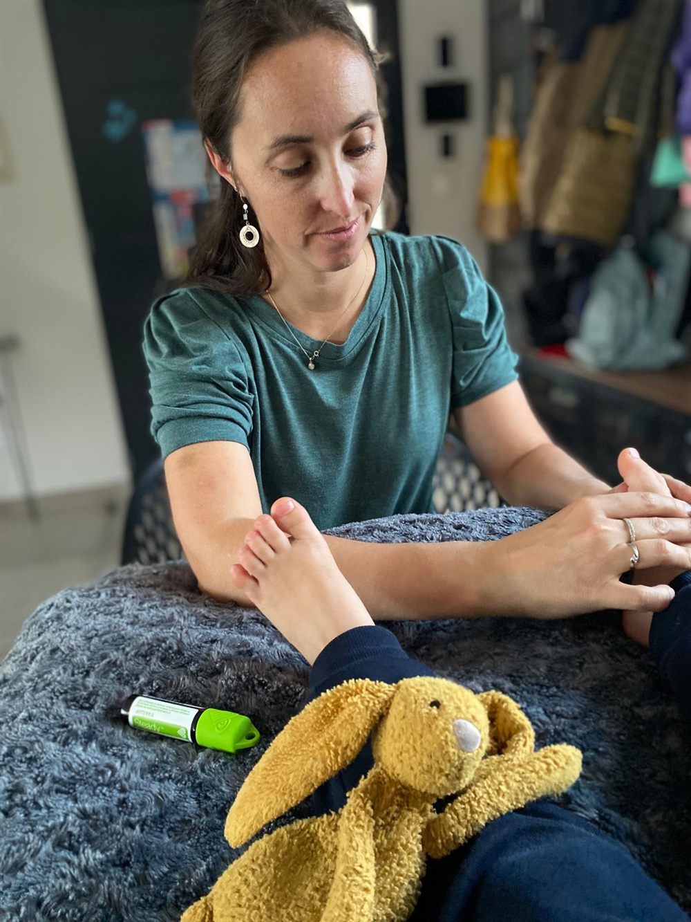 Lucie pendant une séance de réflexologie plantaire avec un enfant, son doudou lapin sur les genoux