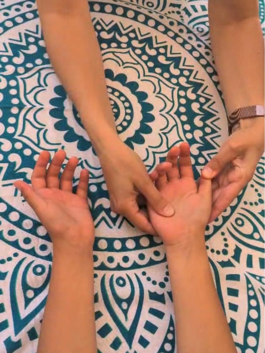 Les mains de Lucie pendant une séance de réflexologie palmaire, sur un tissu à mandala bleu